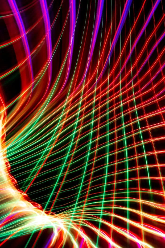 Dynamic abstract image of colorful light trails creating geometric patterns against a dark background.